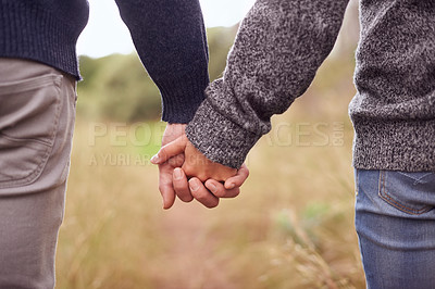 Buy stock photo Cropped shot of a couple holding hands while outside