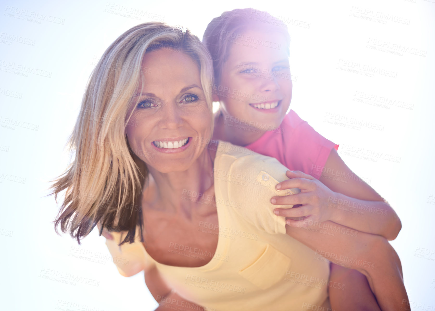 Buy stock photo A smiling mother with her daughter on her back  while outdoors