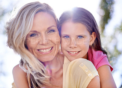 Buy stock photo A smiling mother with her daughter on her back  while outdoors
