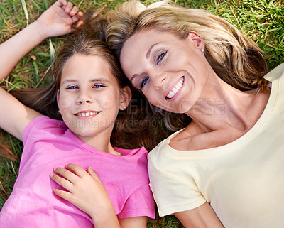 Buy stock photo A happy mother and her young daughter lying on the grass together outdoors and looking up