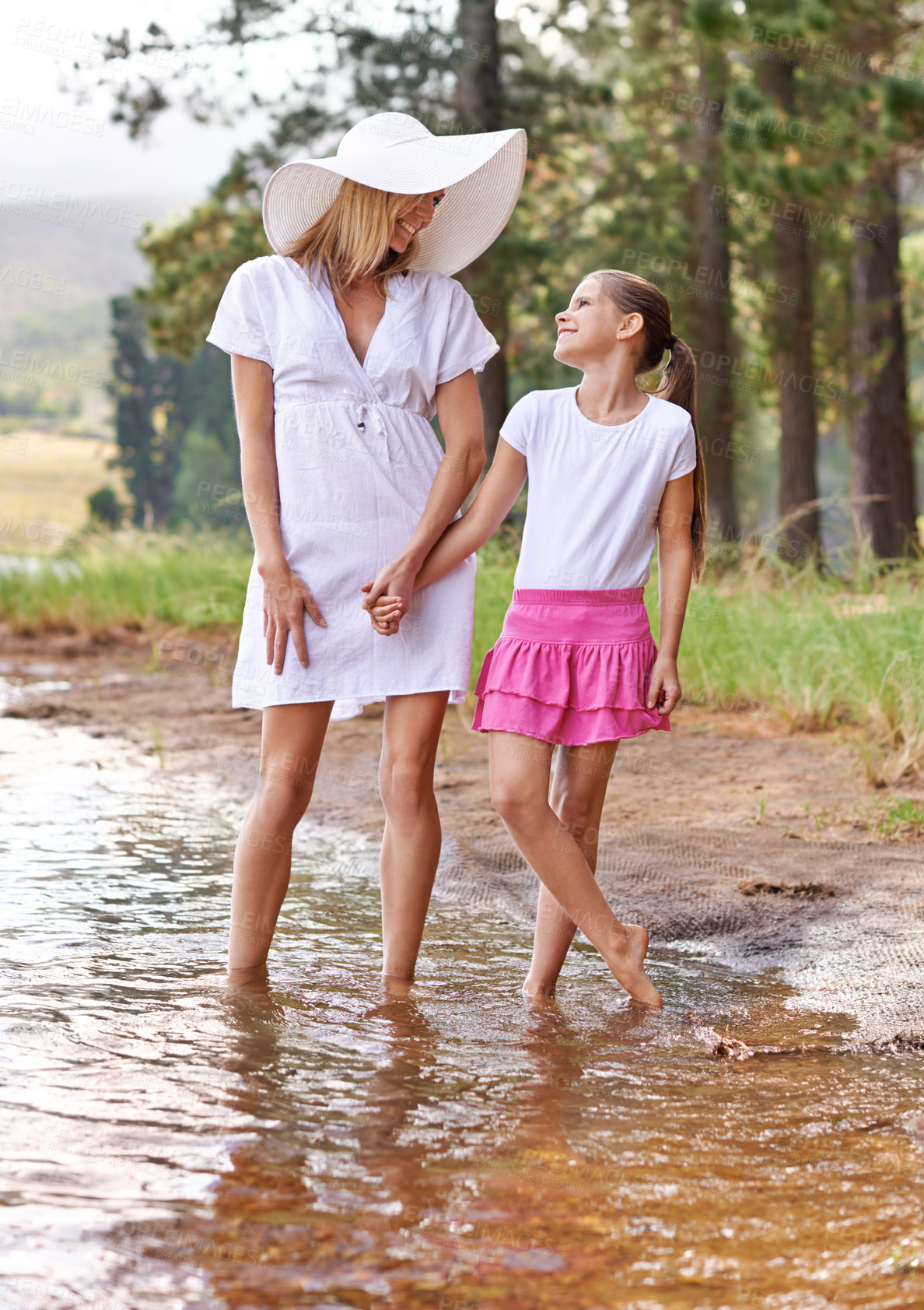 Buy stock photo Mother, daughter and happiness outdoor in lake for bonding, support or holding hands on holiday in nature. Family, woman and girl child with smile or adventure on vacation, travel and river with love