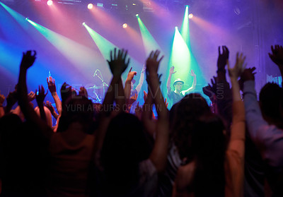 Buy stock photo Fans, people or dancing at concert, music festival or night party, neon lights or event energy. Dance, fun and show, excited crowd in arena and rock band musician in spotlight on stage performance.