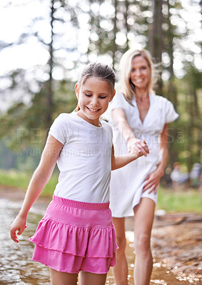 Buy stock photo Mother, daughter and happiness outdoor in lake for bonding, support or holding hands on holiday in nature. Family, woman and girl child with smile or adventure on vacation, travel and river with love