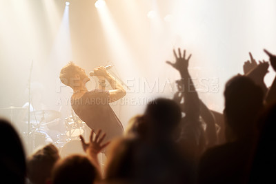 Buy stock photo A rock star singing into his mic while fan reach out their hands to him
