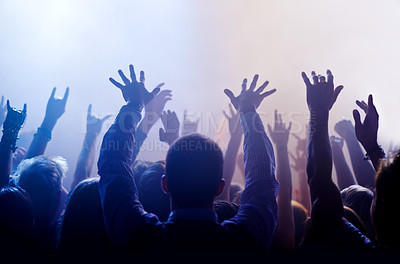 Buy stock photo Music, hands raised and people at concert or festival from back, lights and energy in crowd at live event. Dance, fun and group of excited fans in arena at rock band performance or audience at party.