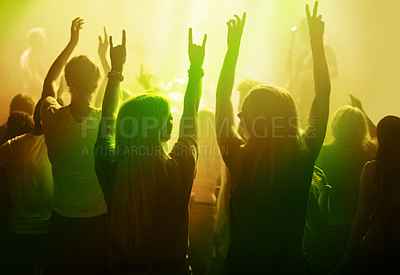 Buy stock photo Rock music, friends and women dancing at concert or festival from back, yellow neon light and energy at live event. Dance, fun and excited fans in arena at band performance or crowd at party together