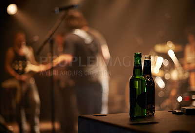 Buy stock photo Two beer bottles on a table as a band plays in the background