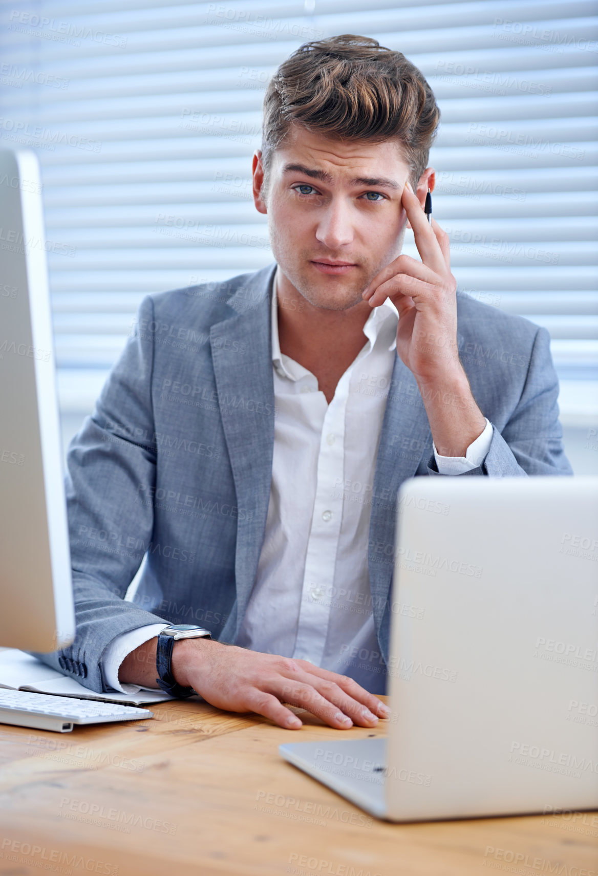 Buy stock photo A bored young businessman seated at his desk