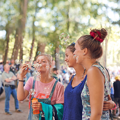 Buy stock photo Festival, woman and friends blowing bubbles outdoor at event or party for celebration in summer. Smile, event and happy young people in nature or forest for concert, entertainment or performance