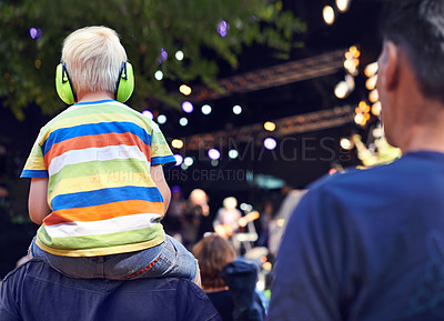 Buy stock photo Rearview shot of a young boy sitting on his father's shoulders at a music concert