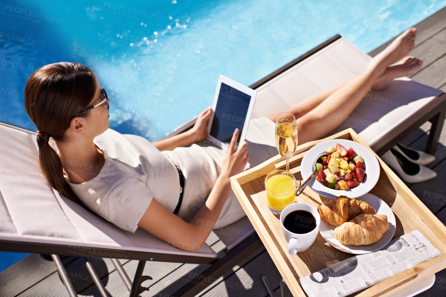 Buy stock photo An attractive young woman enjoying her breakfast poolside