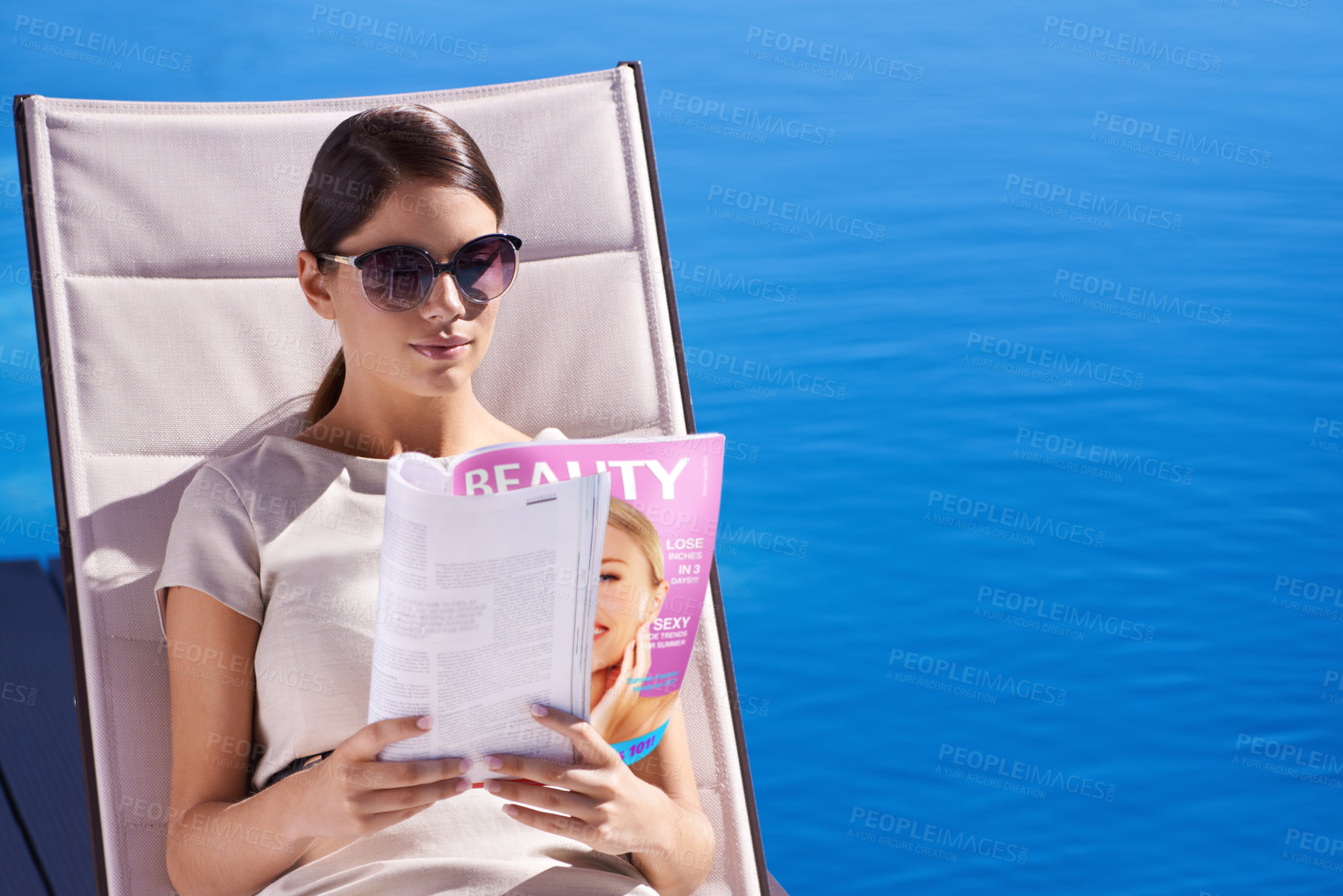 Buy stock photo Woman, reading and magazine on sunbed by pool with sunglasses for relax, article and lifestyle news. Person, publication and paper outdoor on holiday, vacation and summer trip at hotel or resort