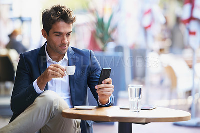 Buy stock photo Shot of a young businessman reading a text while sitting at an outdoor cafe
