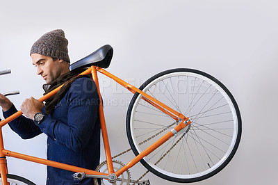 Buy stock photo Cropped shot of a trendy young man carrying his bicycle indoors