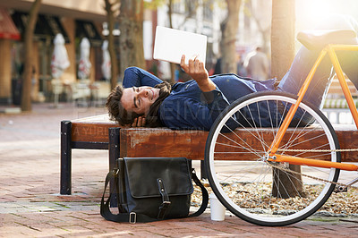 Buy stock photo Shot of a man using his tablet while taking a break in the city with his bicycle beside him