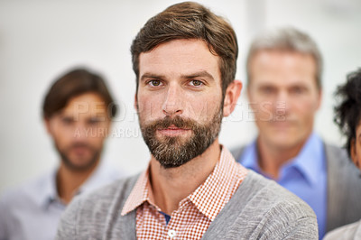 Buy stock photo Cropped shot of a handsome young man standing with his colleagues blurred in the background
