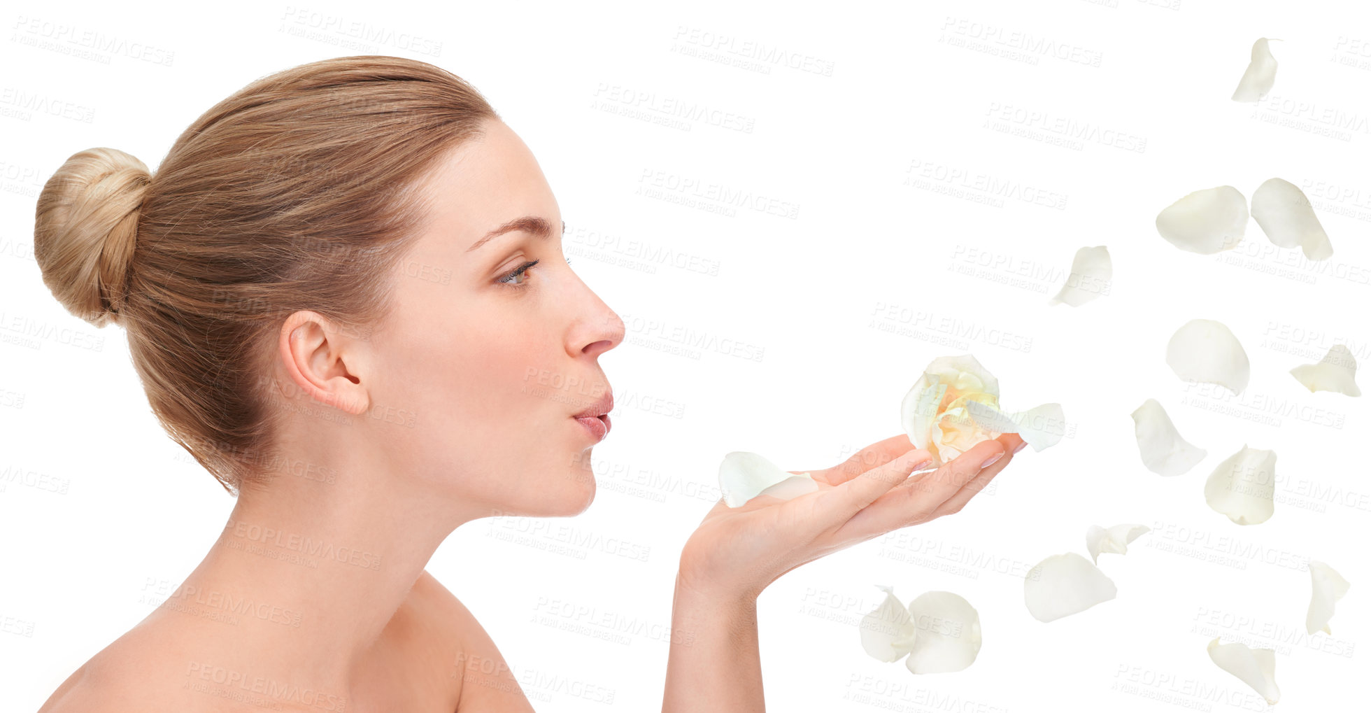 Buy stock photo An attractive young woman blowing rose petals against a white background