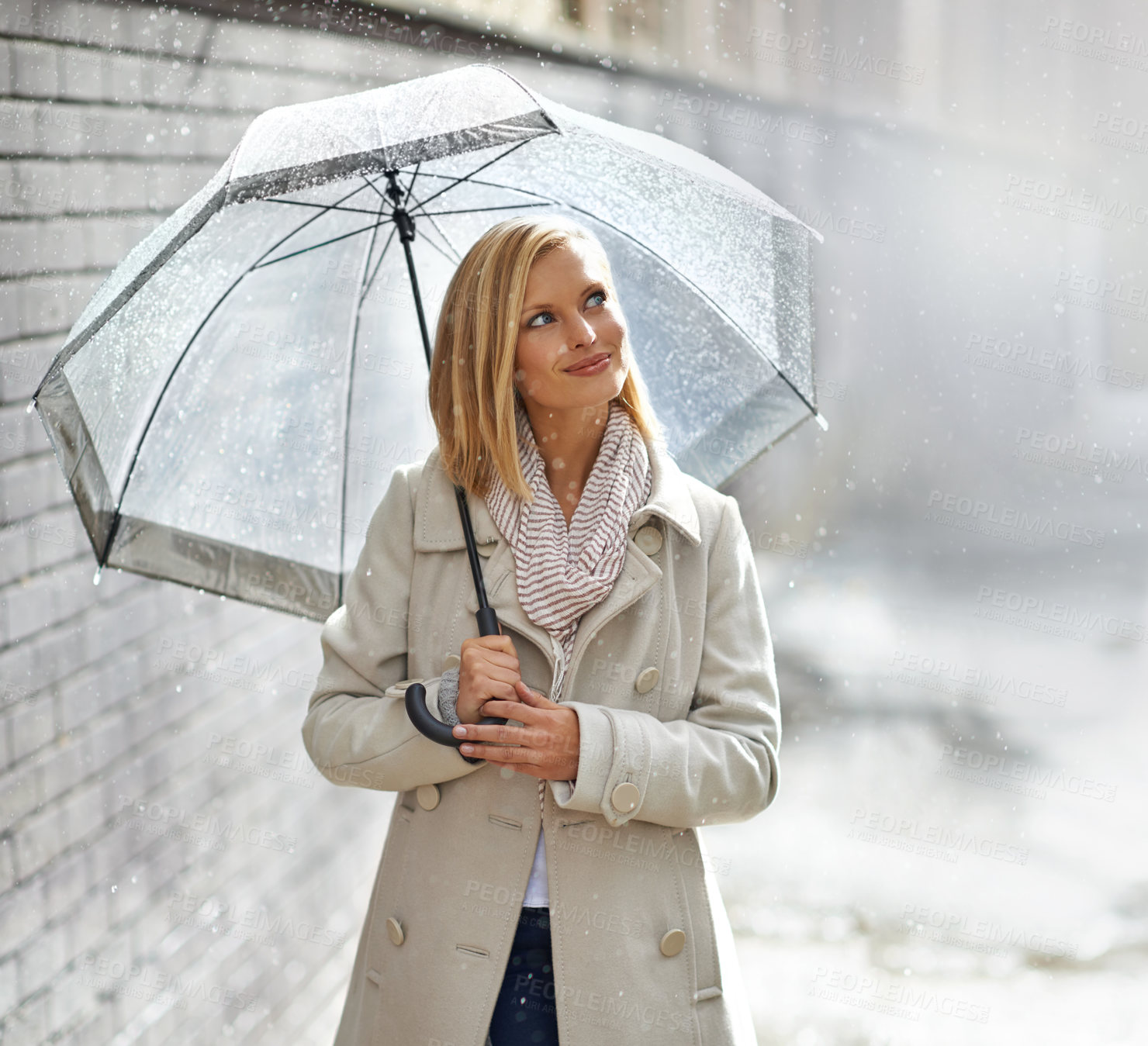 Buy stock photo Shot of a young woman walking down the street with an umbrella on a rainy day
