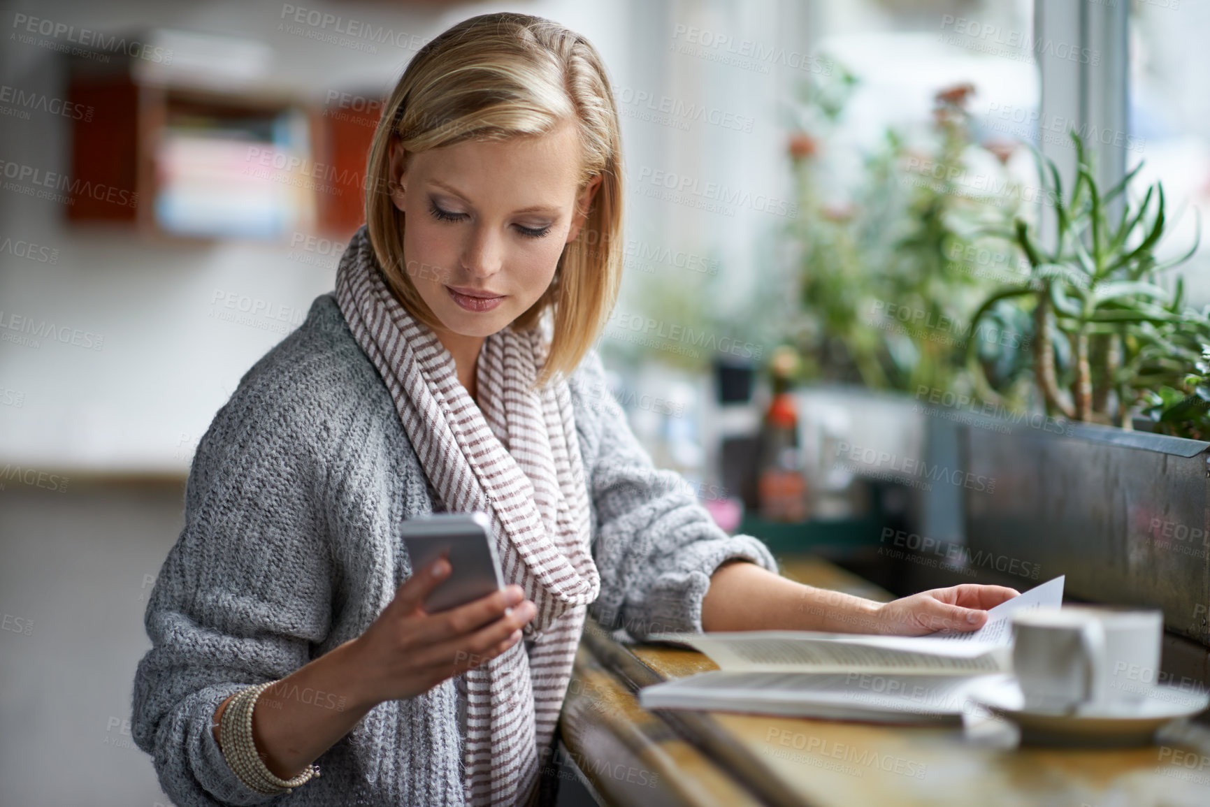 Buy stock photo A young woman sitting in a coffee shop sending a text message