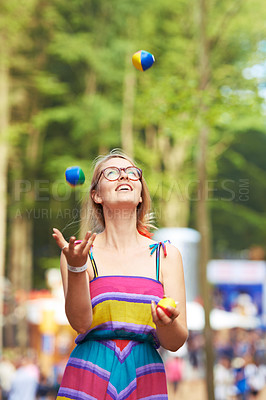Buy stock photo Shot of an attractive young woman juggling at an outdoor festival