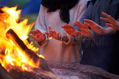Buy stock photo Hands, fire and people camping outdoor, keeping warm with open flame at campsite, friends huddle for heat and bonding. Travel, nature and relax around campfire, community and together for adventure