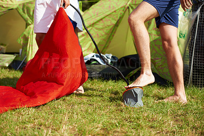 Buy stock photo Camp, nature and people with pump for mattress on outdoor vacation, travel or holiday in field. Grass, legs and friends preparing inflatable bed on campsite with tent on lawn for weekend trip.