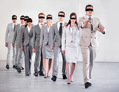 Buy stock photo Shot of a group of blindfolded businesspeople following their equally blind manager