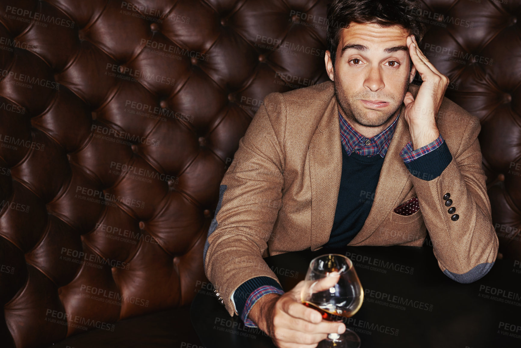 Buy stock photo Portrait, bored and man drinking in a club, expression and relax with event and afterparty. Face, guy on a sofa or person with alcohol and annoyed with a glass, headache and frustrated with culture