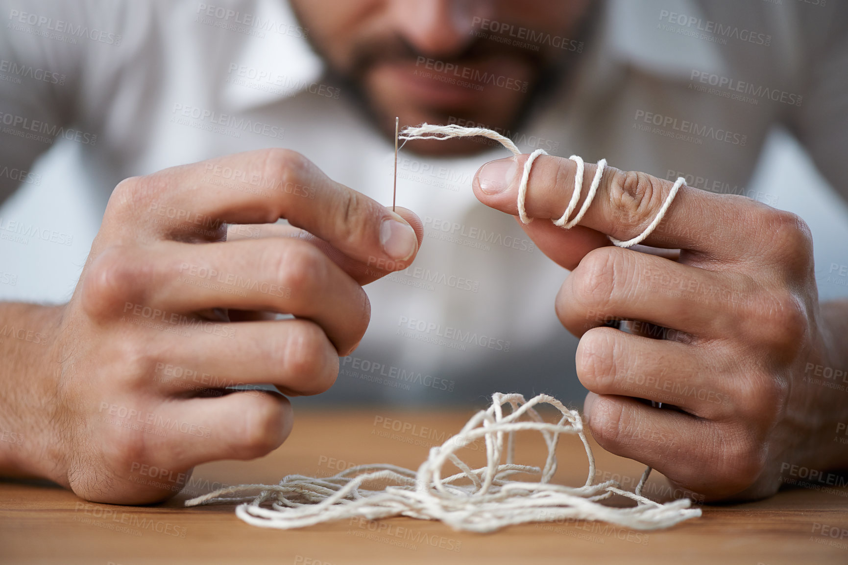Buy stock photo A man struggling to thread string through a needle's eye