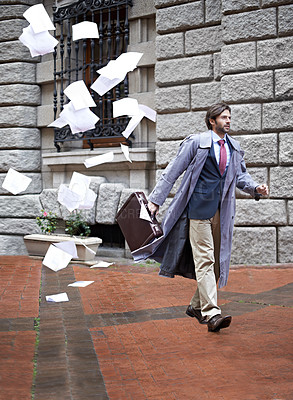 Buy stock photo A businessman unaware that as he walks to work he's losing all his papers