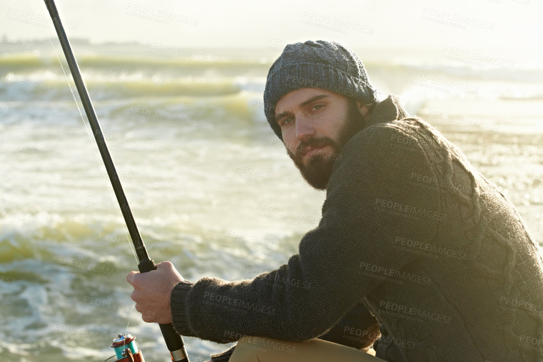 Buy stock photo Cropped shot of a bearded man fishing on the beach
