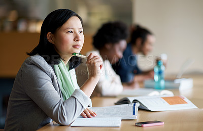 Buy stock photo A young woman studying in the library with another students