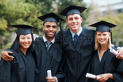 Buy stock photo A group of college graduates standing in cap and gown and holding their diplomas