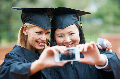 Buy stock photo Two young graduates taking a self-portrait at graduation