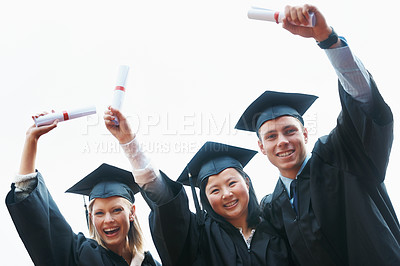 Buy stock photo A group of enthusiastic college graduates holding up their diplomas