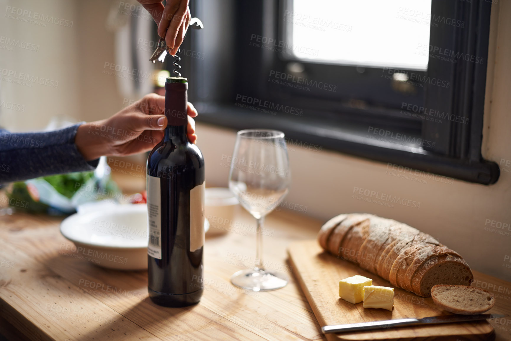 Buy stock photo Hands, opening wine bottle and dinner on table, evening meal with corkscrew and glass, person preparing to drink for enjoyment. Alcoholic beverage, tools with cooking for dining  and bread in kitchen