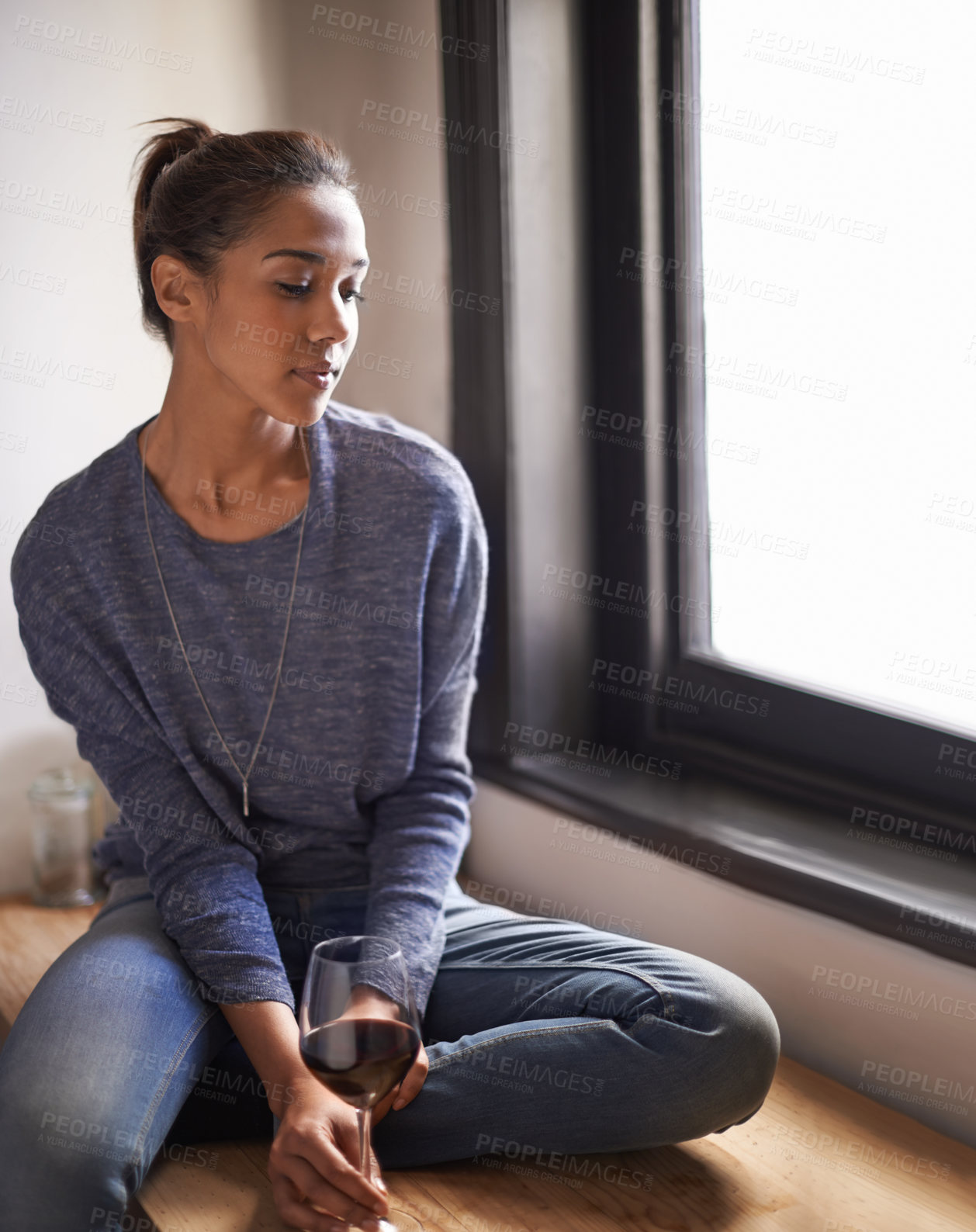 Buy stock photo A young woman sitting in the window sill with a glass of wine