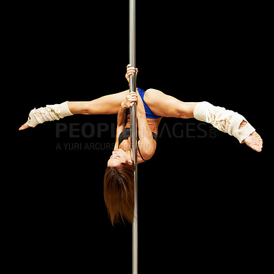 Buy stock photo Studio shot of a young woman hanging upside down on a pole against a black background