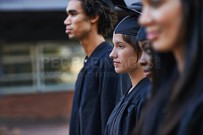 Buy stock photo A group of solemn college graduates lined up at graduation
