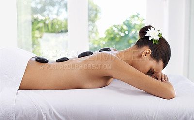 Buy stock photo Hot stone, spine and woman in massage to relax for skincare, beauty and pamper body for wellness at luxury salon. Zen, rocks and back of person at spa for treatment, health and resting in peace