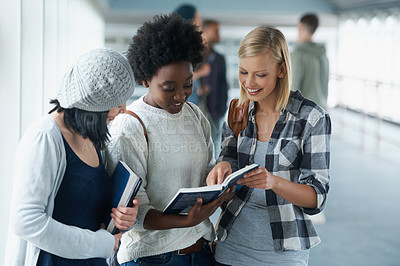 Buy stock photo A group of college students looking at a book together