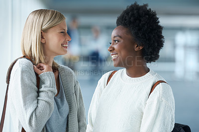 Buy stock photo Two young college students standing together and smiling at one another