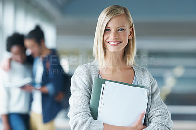 Buy stock photo Portrait of an attractive young college student holding books and standing in a hallway