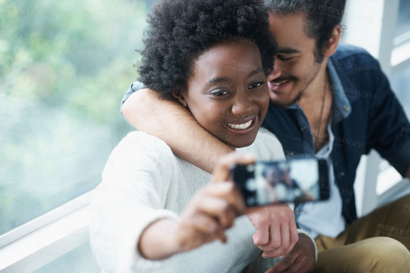 Buy stock photo Couple, smile and selfie for photography of diversity, window and woman happy with boyfriend. People, relax and digital technology indoors with social media to connect online in app with phone