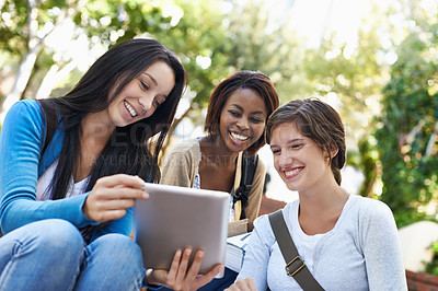 Buy stock photo Shot of a diverse group of college students sitting together outside doing online research