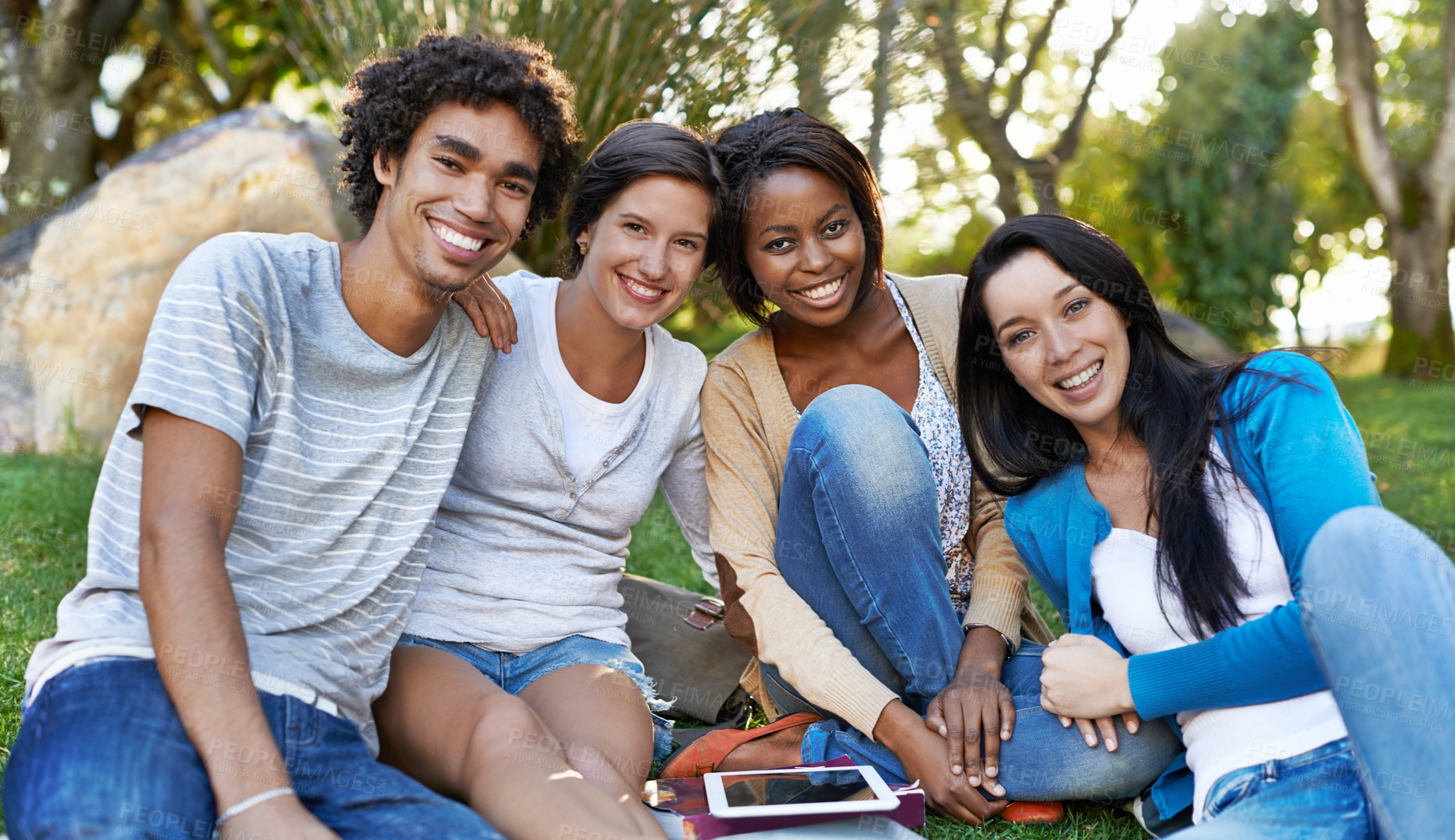 Buy stock photo Shot of a diverse group of college students sitting outside using digital tablet