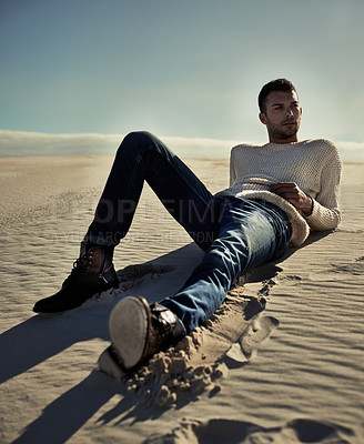 Buy stock photo Full length of a handsome male model lying on the desert sand