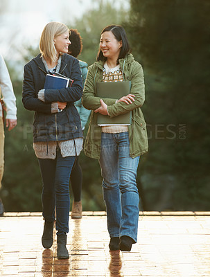 Buy stock photo Students, women and friends on campus for college, conversation while walking to class and smile. University, communication and books for studying, education and academic growth with talk outdoor
