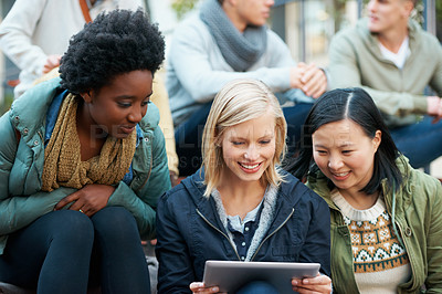 Buy stock photo Shot of a group of university students looking at something on a digital tablet