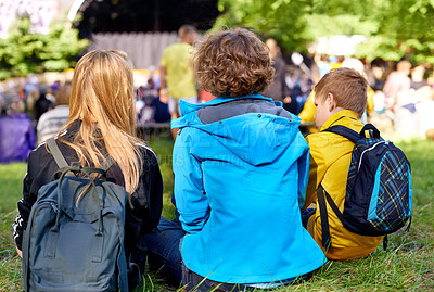 Buy stock photo Rearview shot of three children sitting on the grass during a concert
